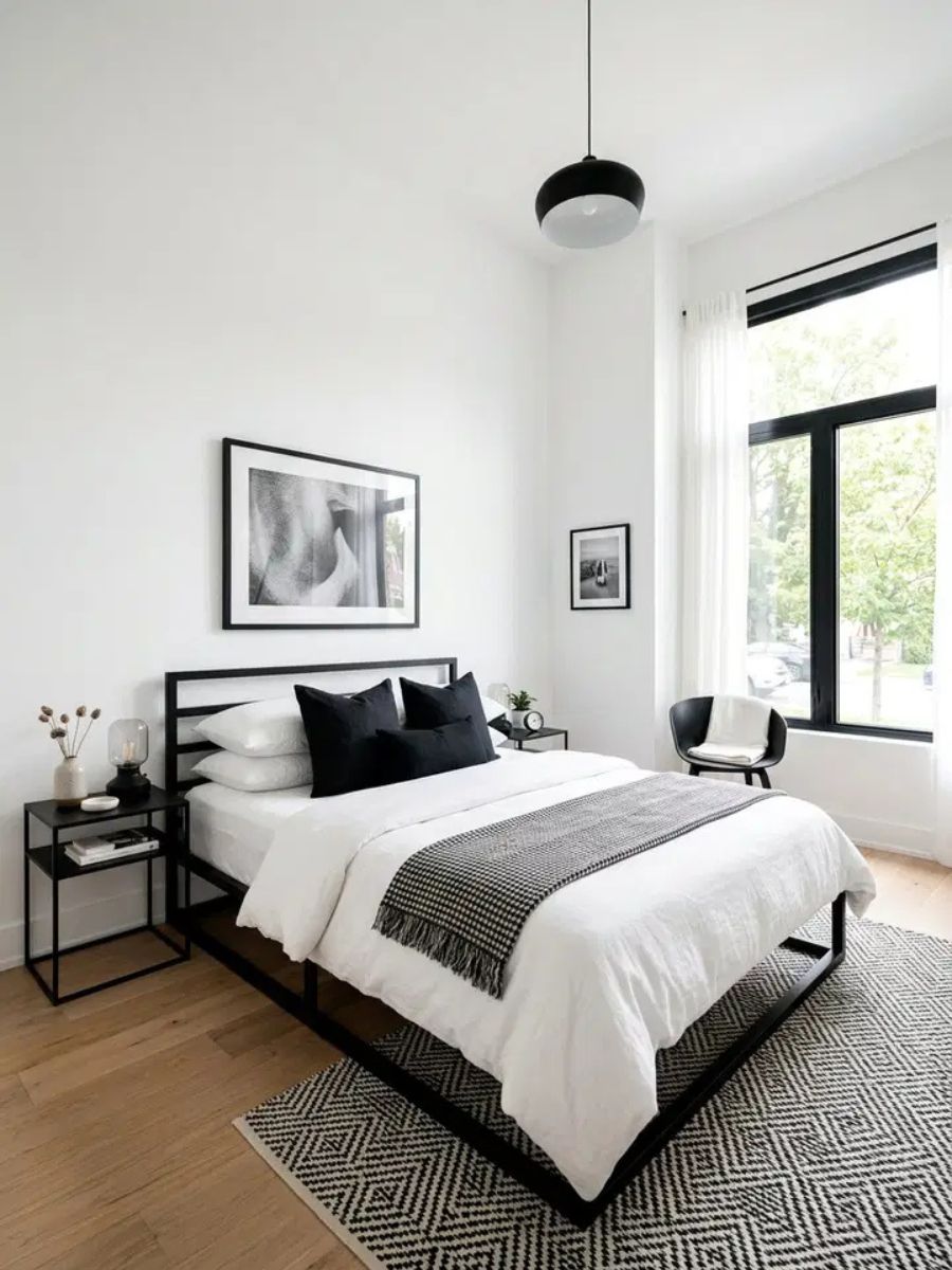 White bedroom with black bed frame, black window trim and monochrome photography on the wall